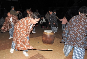 田地餅を囲み、柳の棒を手に稲作を表現する作男たち=菟足神社で