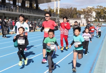 小学生らと走りを楽しむ近藤選手㊧と吉居選手(同左から3人目)=豊橋市陸上競技場で