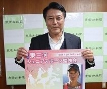 ジュニアスポーツ勉強会のポスターを持つ仲井理事長=東愛知新聞社で