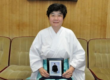 清夫さんの遺影を持つ宮司の白井美穂さん=羽田八幡宮で