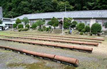 グラウンドに展示する鈴木さんの伐採木作品=いずれも旧門谷小学校で