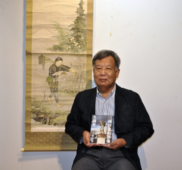「三河の金次郎像全調査」を持つ三浦さんと尊徳を描いた掛け軸=春夏秋冬叢書で