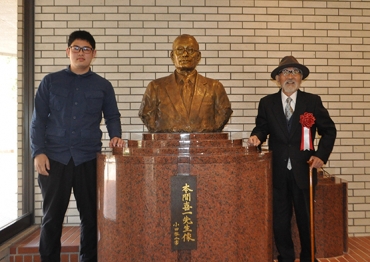 本間氏の胸像と鈴木さん㊧、越知さん=愛知大学豊橋キャンパスで