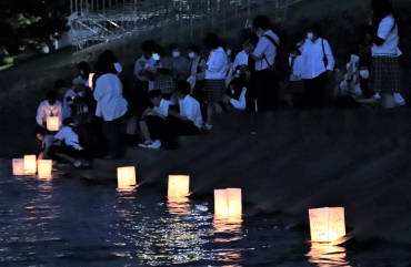 平和を祈って灯籠を流す参加者ら=豊川左岸で