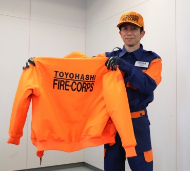 新しい活動服姿で防寒衣を掲げる武田団長
