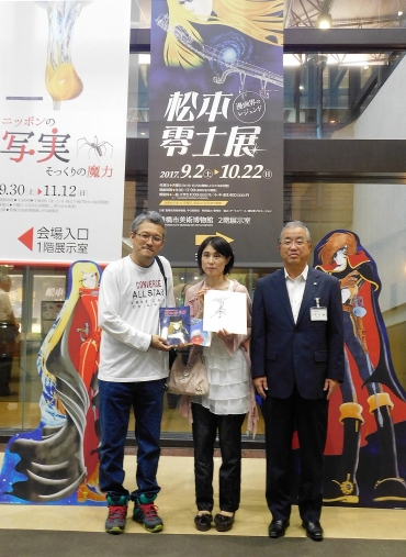 金田副市長㊨から記念品を受けた近藤さん夫妻=豊橋市美術博物館で