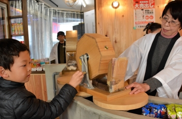木製の福引器を回す子ども=豊橋市の大豊商店街で