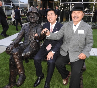 大澤会長の銅像の隣に座る(右から)三澤さん、石川社長=OSGアカデミーで