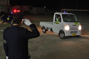 鳥居署長(手前)の見送りを受けて出発する青パト車両=新城市立舟着小学校で