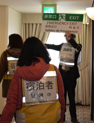 5カ国語で書かれたボードを掲げ外国人宿泊者を避難誘導する従業員=ホテルアソシア豊橋で