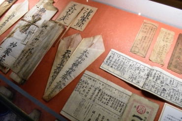 俵の中から見つかったお札やお守りも展示される=大橋屋で