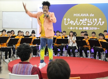 テーマソングを披露するグレコさん=蒲郡市のJR蒲郡駅コンコースで