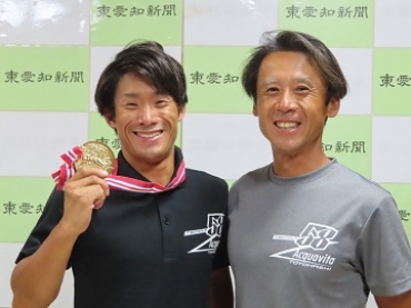優勝メダルを掲げる丸山選手と今枝コーチ=東愛知新聞社で