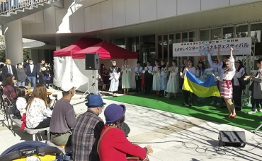 ステージで、国旗を掲げながら母国の歌を披露するウクライナの人々=まちなか広場で