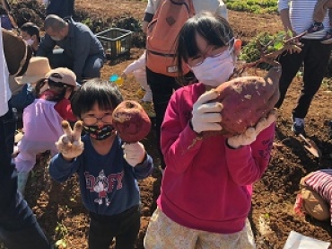 収穫したサツマイモを持つ子どもたち=豊川市千両町で(提供)
