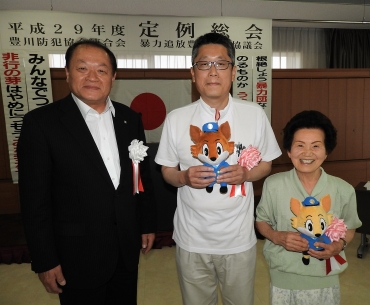 権田会長から感謝される「あんぜんくん」の人形を持つ伴さん㊥と「みはりちゃん」を持つ吉本さん㊨=JAひまわり本店で