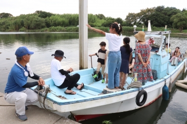 船着き場で子どもらと談笑する荒津さん㊧=牛川町の豊川左岸で