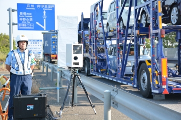 可搬式速度違反自動取締装置㊥を使い、速度違反を取り締まる第二交通機動隊員=国道23号豊橋バイパスで