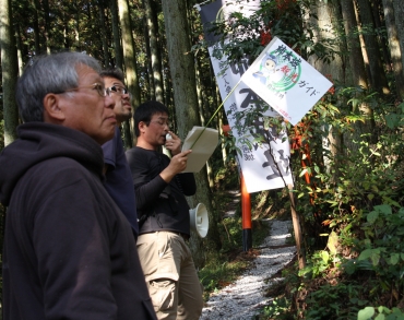 手旗を持って参加者に案内をする杉山さん(右)=新城市下吉田で