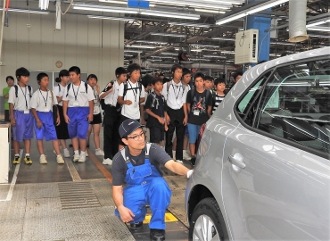 車の整備作業を見学する中学生ら=VGJ豊橋インポートセンターで