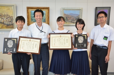 トロフィーと表彰状を手に山西教育長(左から2番目)に喜びを報告する生徒たち=市役所で