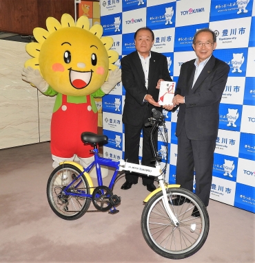 権田組合長㊨から折り畳み自転車の寄贈を受けた山脇市長=豊川市役所で