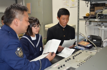 校内放送で呼び掛ける生徒と安澤巡査部長=二川中学校で