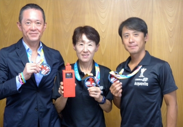 メダルを手に完走を喜び合う(左から)石川社長、鹿野さん、今枝コーチ=東愛知新聞社で