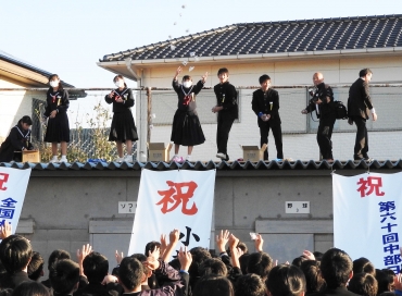 生徒らに向かって紅白餅をまく生徒会や教員ら=小坂井中学校で