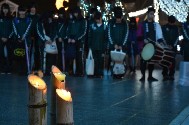 神戸の追悼行事で譲り受けてきた竹とうろうを囲み黙とうする生徒ら=豊橋駅東口ペデストリアンデッキで