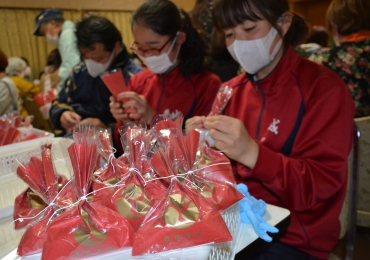 タンキリあめの袋詰め作業を手伝う豊城中学校生徒ら=安久美神戸神明社で