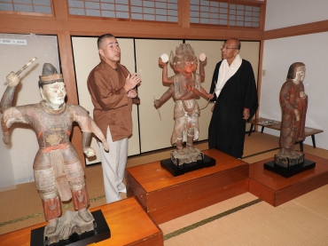 八坂さん㊧から修復された木像の説明を受ける西本住職。木像は左から毘楼勒叉天、阿修羅王、大弁功徳天とされる=財賀寺で