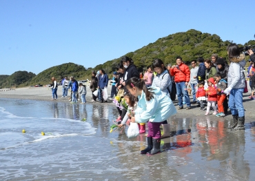 波打ち際から花を流す参加者=小島海岸で