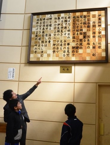 開校後、3年間の卒業生が一文字ずつ彫って出来上がった校歌額。左は太田さん=伊良湖岬小学校で