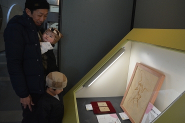 羽毛の化石を見つめる子ども=豊橋市自然史博物館で