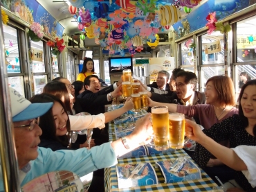 ジョッキを手に乾杯するビール電車試乗会の乗客=豊橋市内で