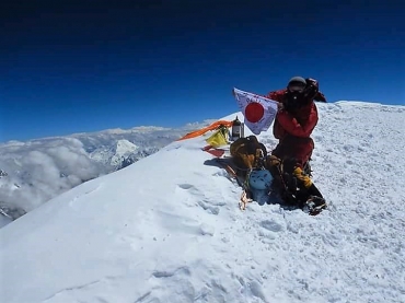 K2の山頂で日の丸を広げる稲吉さん(本人提供)
