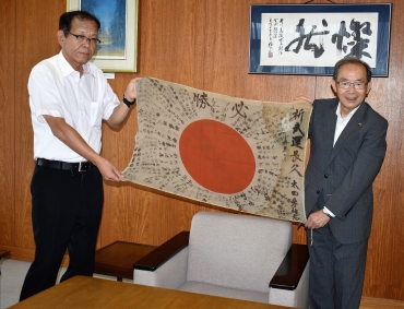 山脇市長と、祖父の日章旗を広げる太田芳則さん㊧=豊川市役所で