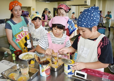 缶詰を使った料理に挑戦する親子ら=豊川市勤労福祉会館で