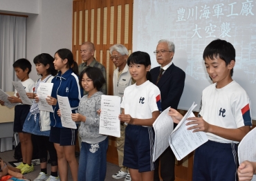 グループのメンバーから空襲に関する資料を贈られた代田小の児童ら=豊川市平和交流館で
