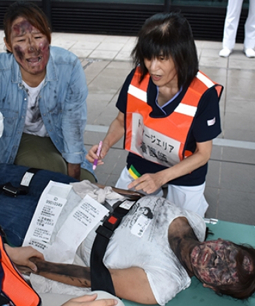 泣き叫ぶ付き添い役の女性㊧にも対応しながら、傷病者の状態を判別する職員=豊川市民病院で