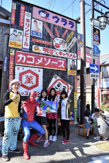 ホーロー看板を背に記念撮影を楽しむ女子高生ら=豊川稲荷表参道で