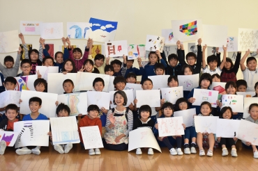 個性豊かな児童の作品に囲まれ、笑顔の吉澤さん㊥=豊小学校で