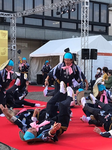 パフォーマンスで寝転がる若葉祭笹踊りのヤンヨー神(豊川市観光協会提供)