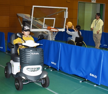 電動車いすや競技用車いすに試乗する子どもたち=豊川市総合体育館で