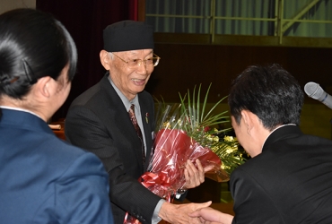 花束を贈られ、笑顔で生徒と握手する大村氏㊥=小坂井高校で