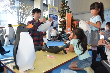 和田さん㊧に教わりながらイワトビペンギンを作る子どもたち=ここにこで