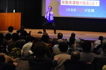 簡単な有酸素運動を参加者と実践する福富さん=豊川市文化会館で