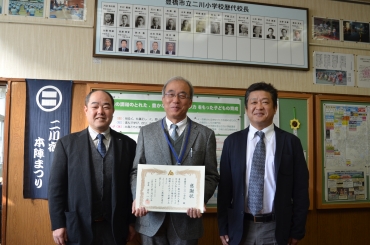 感謝状を手にする鈴川校長㊥。左は水野部会長と右は宮田委員長=二川小学校で