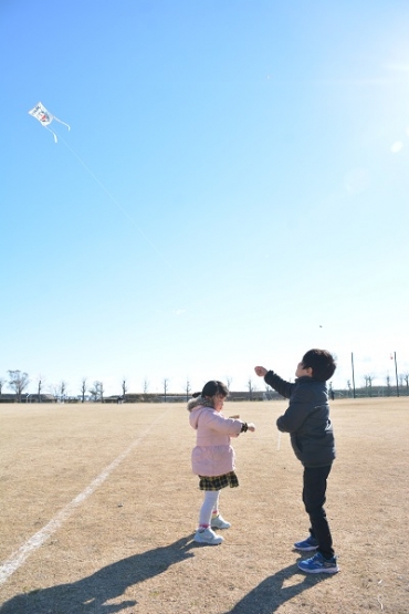 キャラクターが描かれた凧を空高く上げる子どもたち=豊橋総合スポーツ公園で
